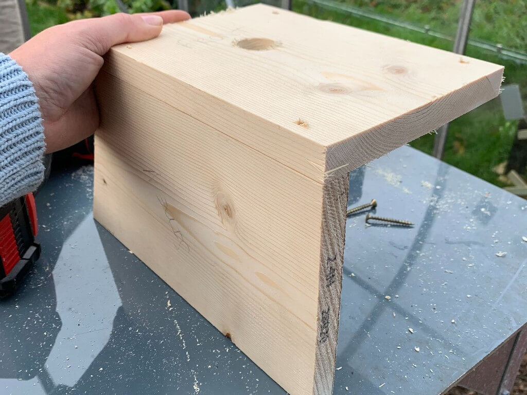 Outside image of the bird box getting two wood pieces attached together.