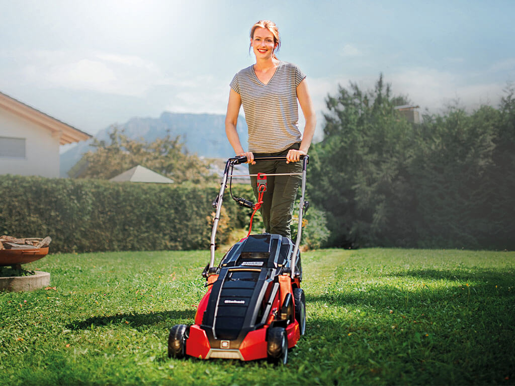 A woman mows her lawn with an electric lawnmower from Einhell.