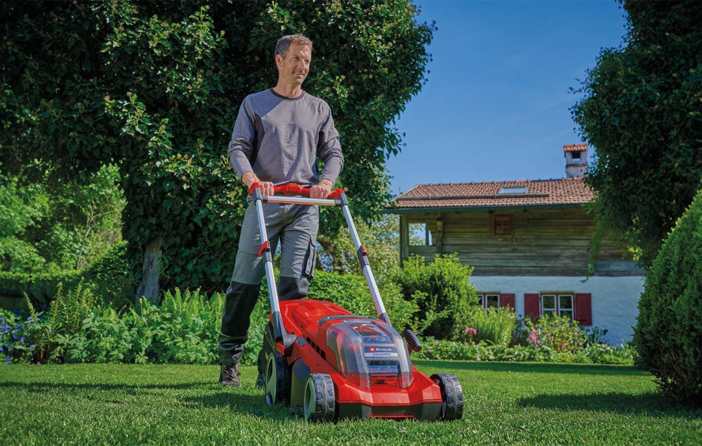 A man mowing the lawn in a garden with a cordless lawnmower with mulching adapter.