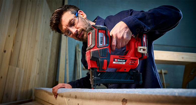 A man is stapling with the Einhell FIXETTO